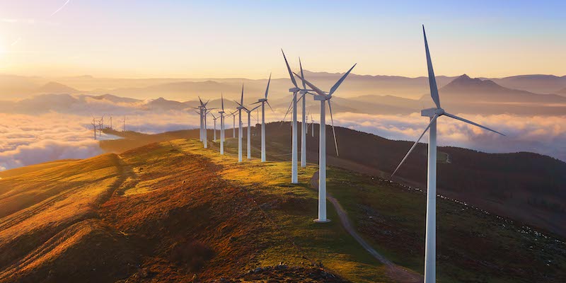 A row of wind turbines grace a mountain ridge at sunset