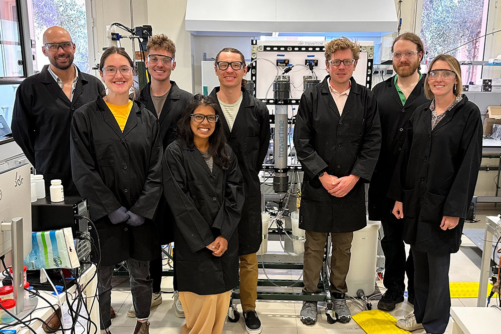 The Travertine team in black lab coats in front of equipment in their lab