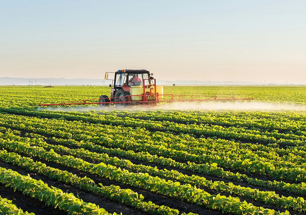 Tractor in a field with a boom sprayer applying fertilizer
